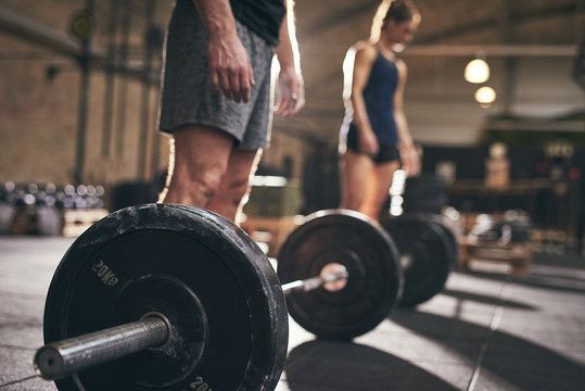 Individuals preparing for barbell strength training session in a gym